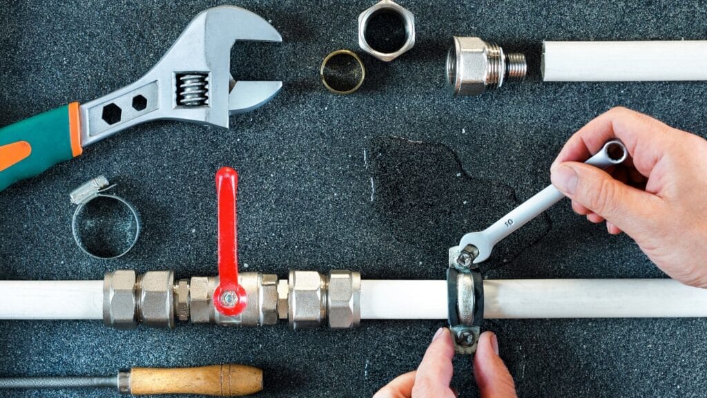 Plumber repairing a pipe valve with an adjustable wrench in Boca Raton