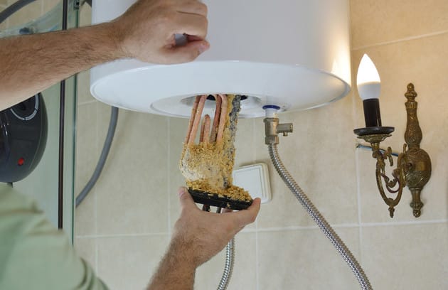 Technician removing mineral buildup from a water heater in Boca Raton