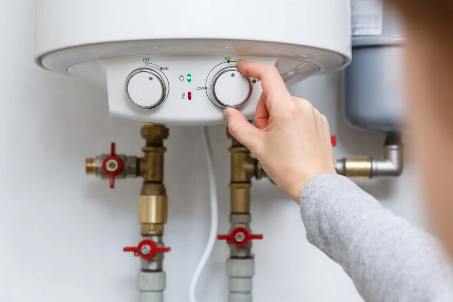 Homeowner adjusting the temperature controls on a water heater in Boca Raton